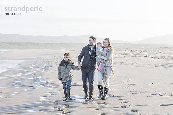 Südafrika  Kapstadt  junges Paar mit zwei Kindern  die am Strand spazieren gehen