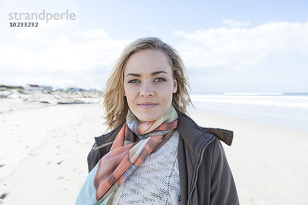 Südafrika  Kapstadt  Porträt einer lächelnden Frau  die am Strand steht.