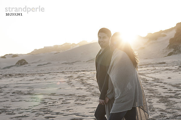 Südafrika  Kapstadt  junges Paar bei Sonnenuntergang am Strand spazieren gehen
