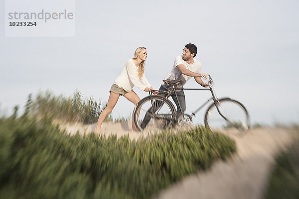 Junges Paar mit Fahrrad auf einer Stranddüne