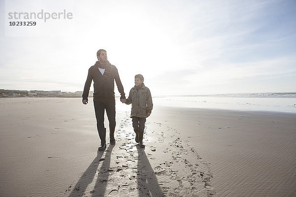 Südafrika  Witsand  Vater und Sohn beim Spaziergang am Strand im Gegenlicht