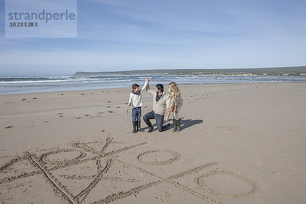 Südafrika  Witsand  Familie spielt tic tac toe am Strand