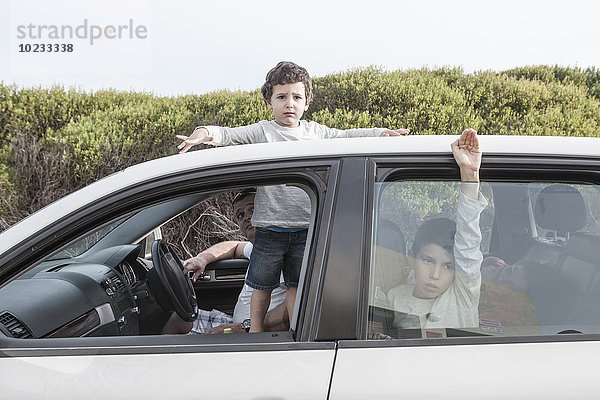 Junge schaut durch ein Schiebedach eines Familienautos