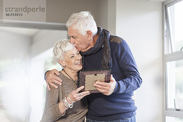 Seniorenpaar mit Bilderrahmen zu Hause