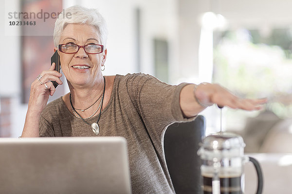 Seniorin mit Laptop am Telefon