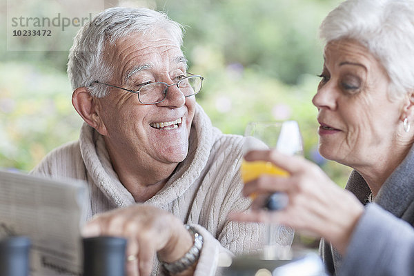 Seniorenpaar beim gemeinsamen Frühstück auf der Terrasse