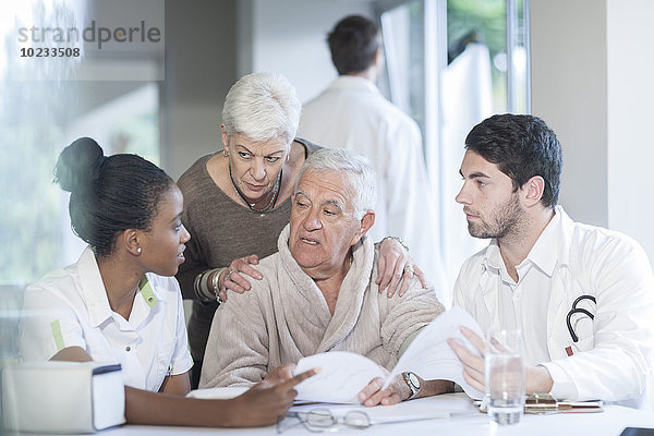 Seniorenpaar in der Klinik im Gespräch mit Arzt und Krankenschwester