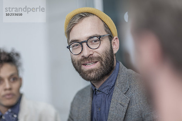 Mann mit Brille und gelber Mütze im Gespräch mit Kollegen