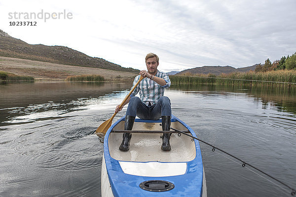 Portrait eines jungen Mannes mit Angelrute auf einem See