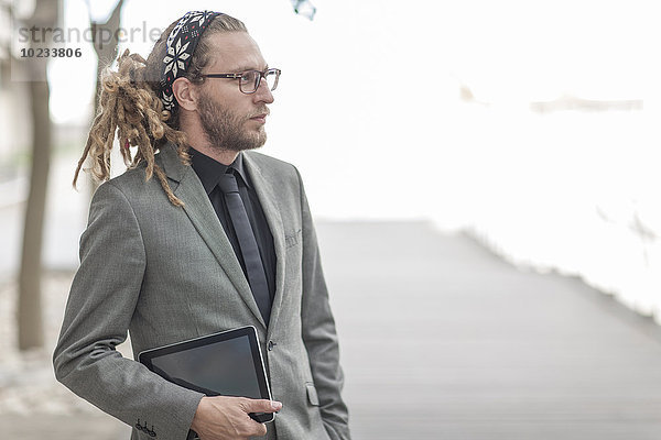 Portrait eines Geschäftsmannes mit Dreadlocks im Anzug mit digitalem Tablett