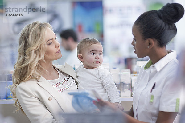 Apothekerin bei der Betreuung des Kunden mit Baby in der Apotheke