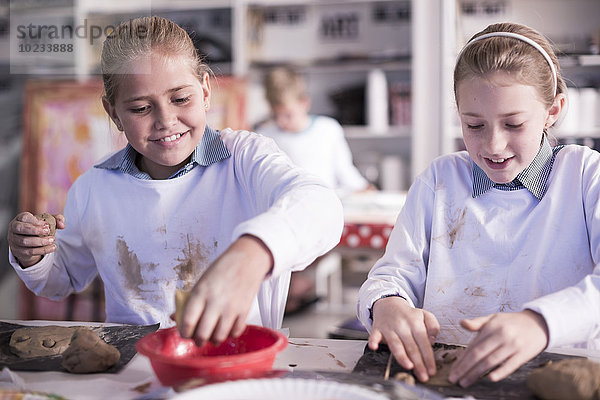 Zwei Mädchen  die in der Kunstklasse in der Schule an der Modelliermasse arbeiten.