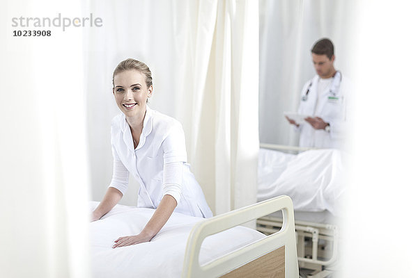 Lächelnde Krankenschwester macht Krankenhausbett