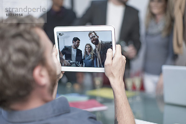 Mann fotografiert Kollegen auf einem digitalen Tablett