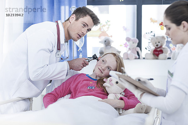 Junge Ärztin untersucht Mädchen im Krankenhausbett