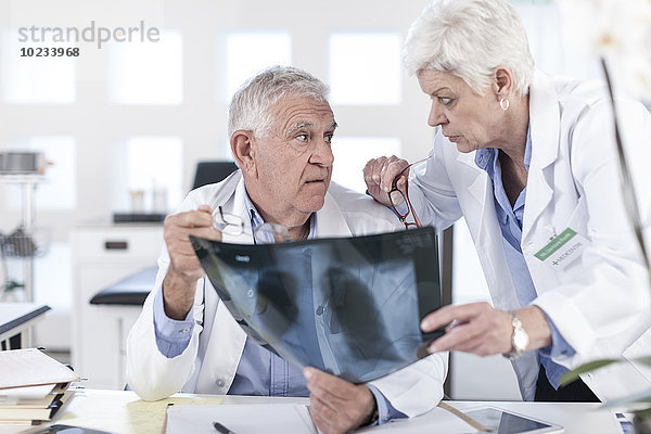Zwei Ärzte am Schreibtisch diskutieren über Röntgenaufnahmen