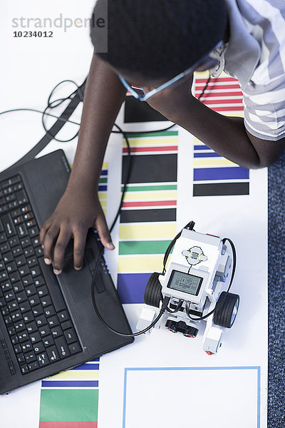 Schuljunge mit Laptop im Robotikklassen-Testfahrzeug auf der Teststrecke