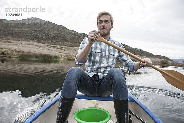 Portrait eines jungen Mannes beim Paddeln auf einem See
