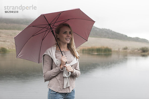 Junge Frau im Regen stehend mit Regenschirm