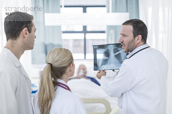 Drei Ärzte mit Röntgenbild im Krankenhauszimmer
