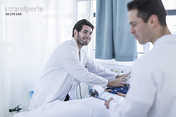 Zwei Ärzte  die einen Patienten in einem Krankenhauszimmer untersuchen.