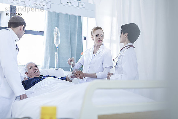 Zwei Ärzte  Krankenschwester und ein Patient in einem Krankenhauszimmer