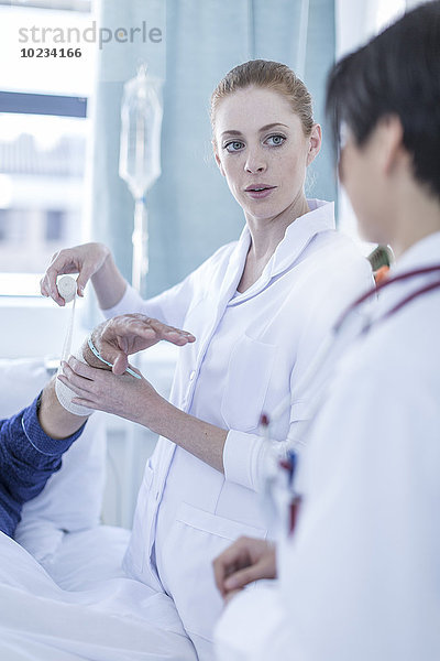 Portrait eines Krankenschwesterbandagierarms eines Patienten im Krankenhaus