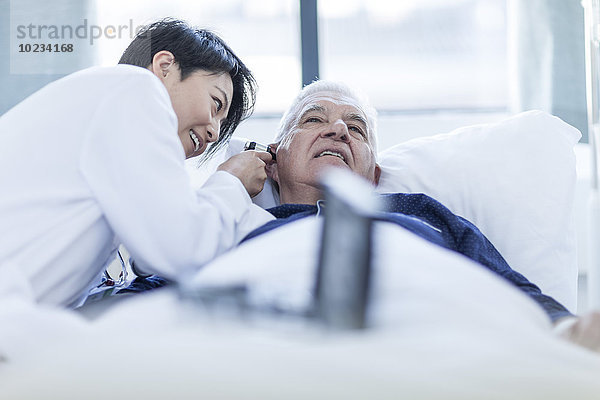 Arzt untersucht Patient mit Otoskop im Krankenhaus