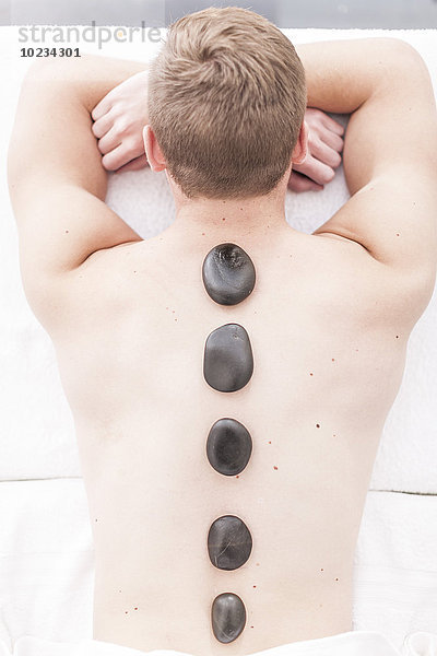 Mann  der eine Hot-Stone-Massage in einem Spa erhält.