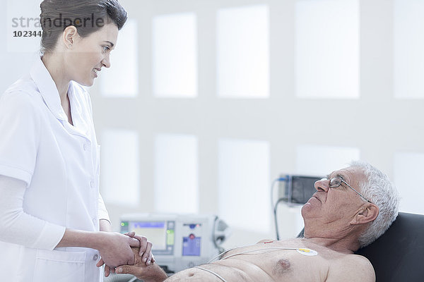 Ein älterer Mann  der im Krankenhaus nachsieht  eine Krankenschwester  die ihn beruhigt.