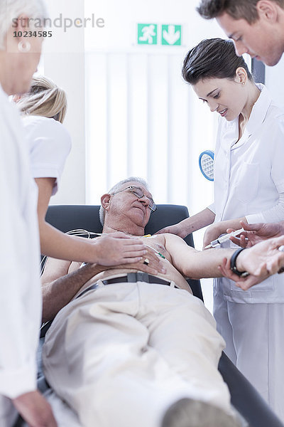 Ein älterer Mann im Krankenhaus bekommt eine Spritze.