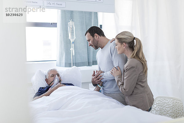 Ehepaar zu Besuch bei einem älteren Patienten im Krankenhaus