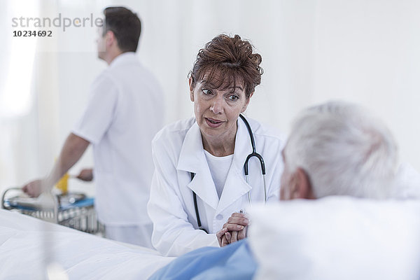 Ärztin zu Besuch beim Senior im Krankenhausbett