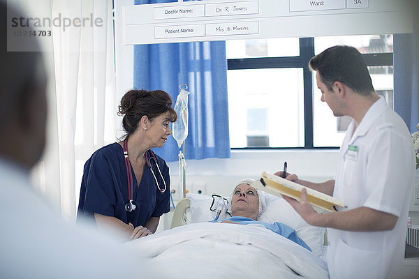 Arzt und Krankenschwester mit Patient im Krankenhausbett