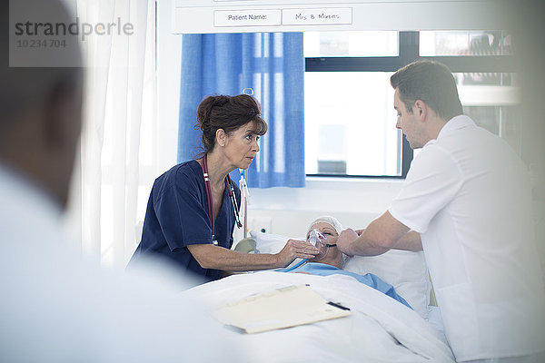 Arzt und Krankenschwester applizieren Sauerstoffmaske am Patienten im Krankenhausbett
