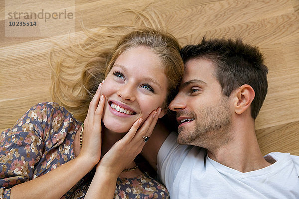Draufsicht auf lächelndes junges Paar auf dem Boden liegend