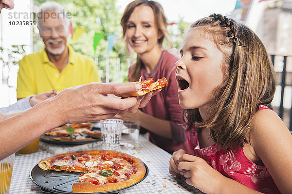 Mädchen wird auf der Familienfeier mit hausgemachter Pizza gefüttert.