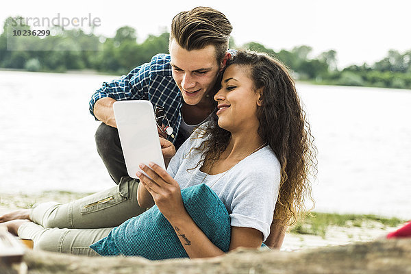 Lächelndes junges Paar mit digitalem Tablett im Freien