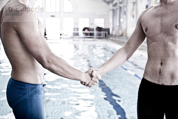 Zwei Schwimmer im Hallenbad beim Händeschütteln
