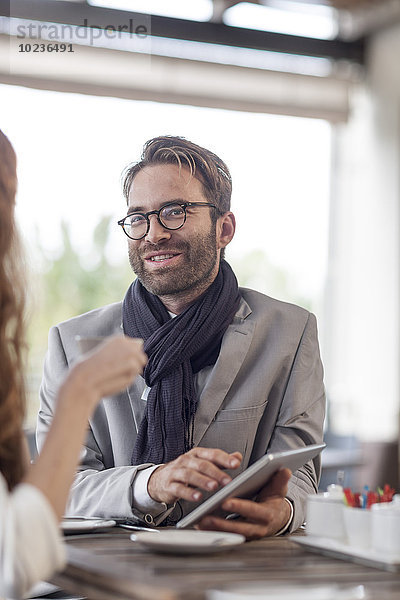 Porträt eines lächelnden Mannes mit digitalem Tablett im Restaurant
