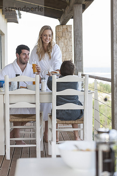 Familie auf der Terrasse des Strandhauses beim Frühstücken