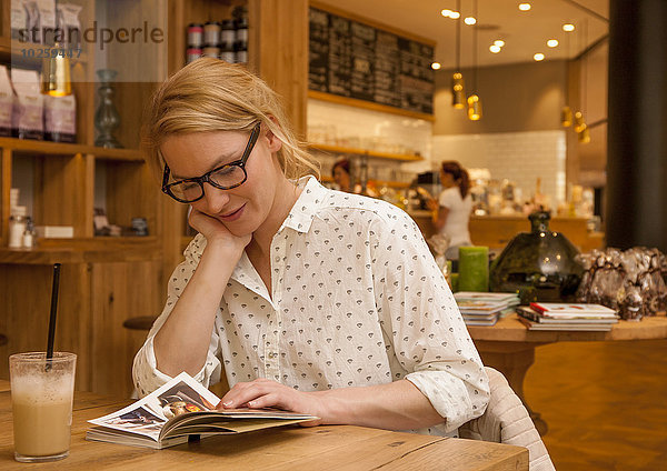 Frau sitzt in Kaffeehaus und liest