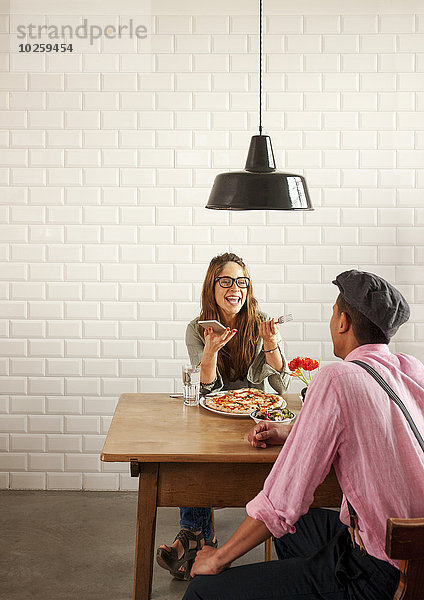 Frau und Mann sitzen sich gegenüber an einem Tisch  essen Pizza