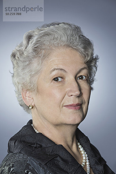 Porträt einer selbstbewussten Seniorin über grauem Hintergrund