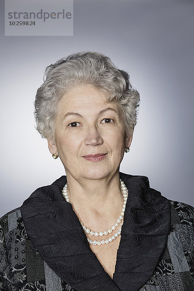 Porträt einer selbstbewussten Seniorin über grauem Hintergrund