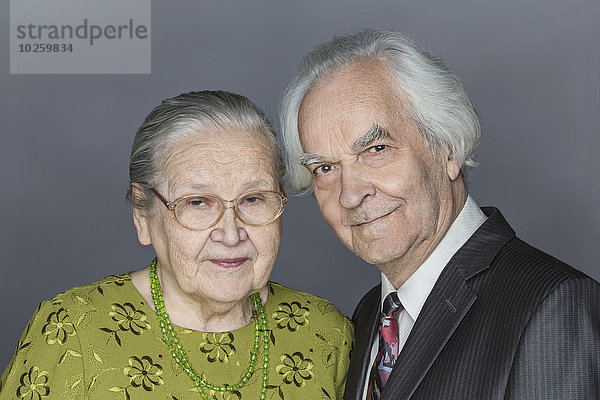 Porträt eines glücklichen älteren Paares über grauem Hintergrund