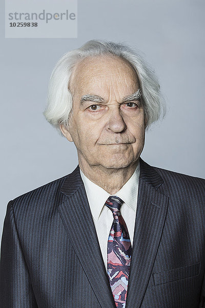 Porträt eines selbstbewussten älteren Mannes vor grauem Hintergrund