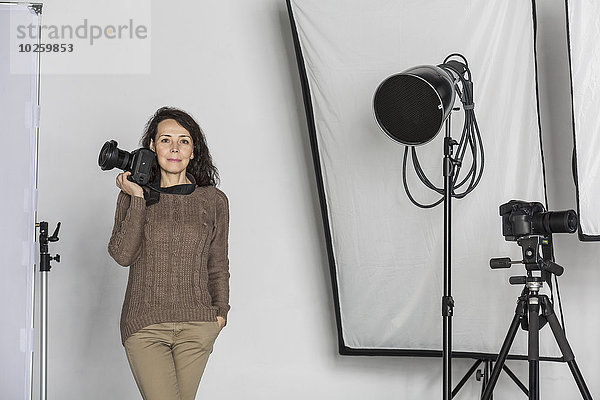 Portrait einer reifen Fotografin mit Kamera im Fotostudio