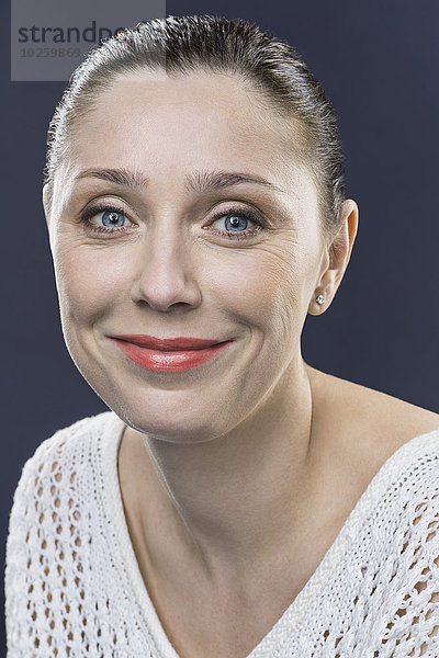Nahaufnahme Porträt einer lächelnden erwachsenen Frau über grauem Hintergrund