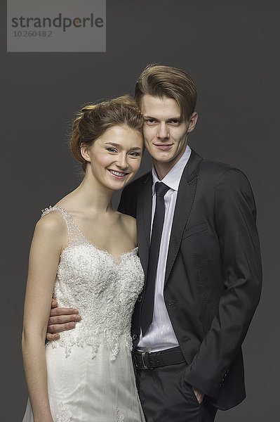 Porträt eines glücklichen Brautpaares vor grauem Hintergrund
